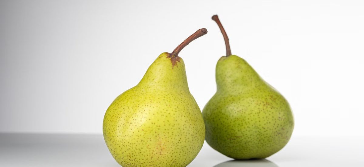 Bright and fresh green pears on a clean white background, symbolizing healthy eating and fresh produce.
