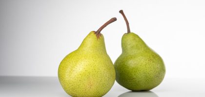 Bright and fresh green pears on a clean white background, symbolizing healthy eating and fresh produce.