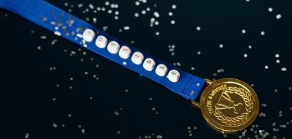Close-up of a gold medal on a blue ribbon with 'possible' beading, symbolizing achievement.